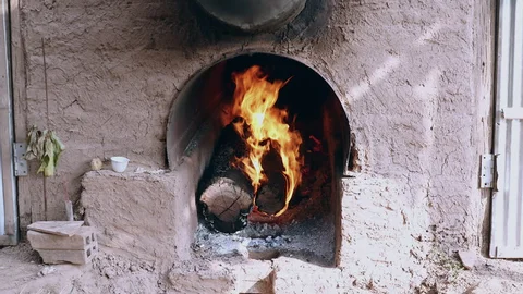 Wood-fired furnace mouth feeding heat into a curing barn flue